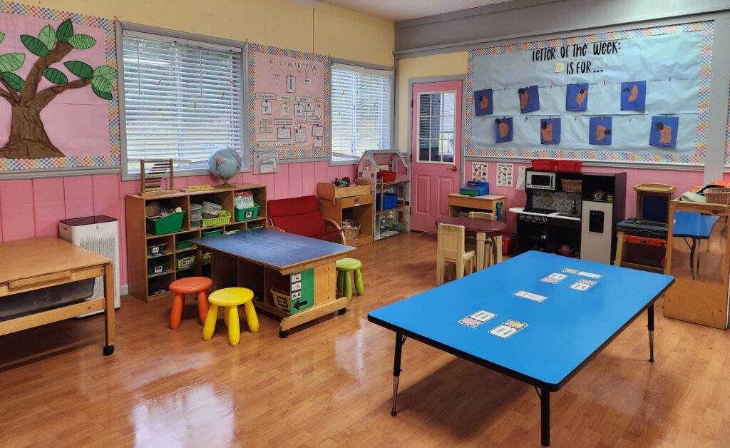 Classroom with blue tables, small chairs and a play kitchen