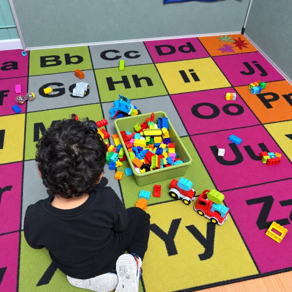 Child building with blocks on the alphabet rug