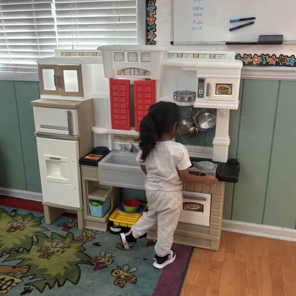 Child playing at the pretend kitchen in dramatic play