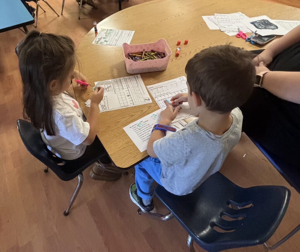 Two children working on worksheets together at a classroom table