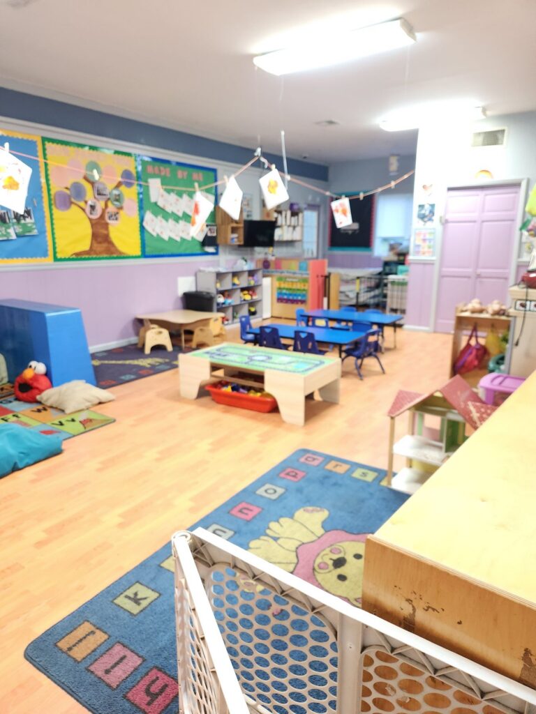 Toddler classroom with play areas and an alphabet rug