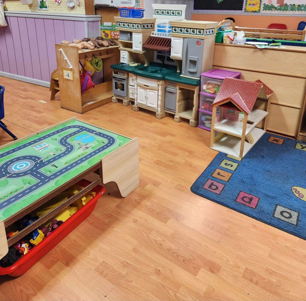 Toddler classroom with a pretend kitchen and train table