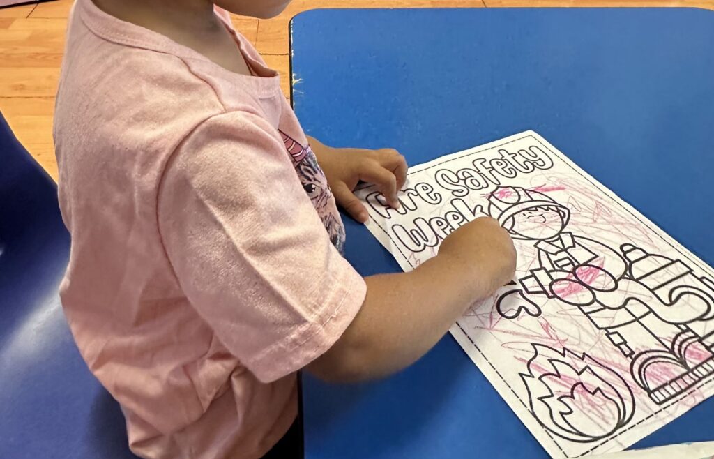 Child coloring a Fire Safety Week page