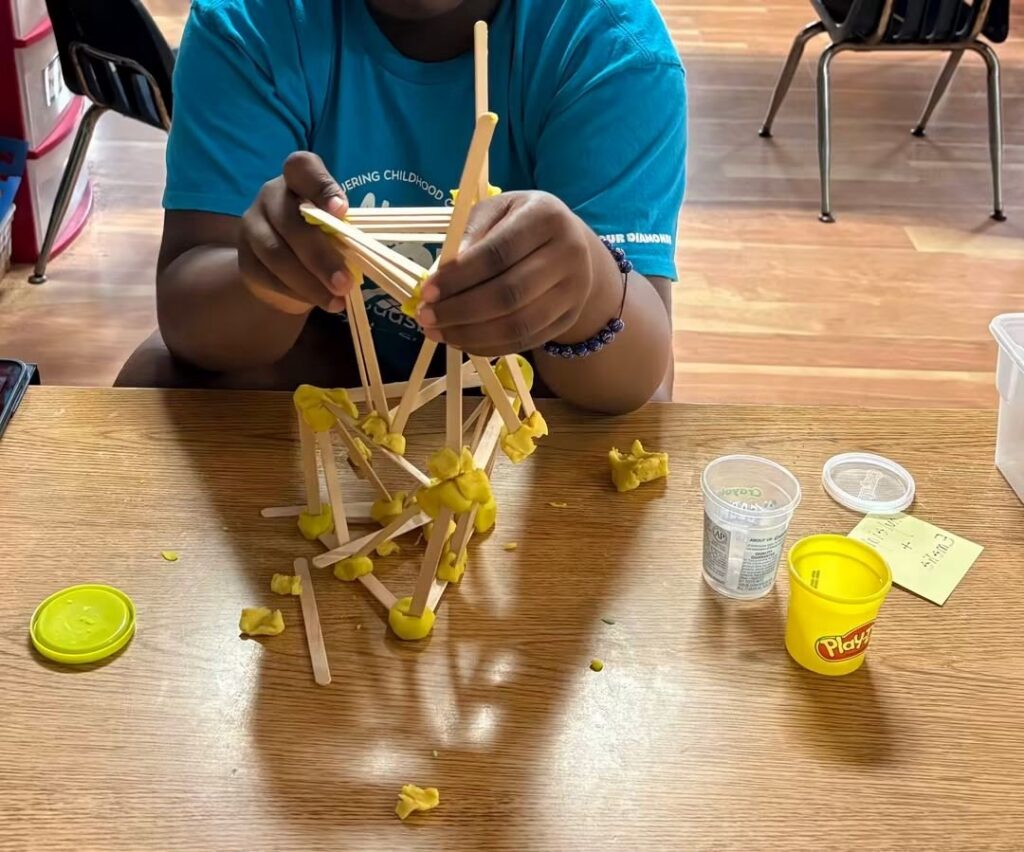 Summer camper building a tower with craft sticks and dough